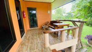 a porch with a wooden bench and a table at Moon River Resort Phimai in Pi Mai