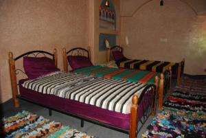 two twin beds in a room with a rug at Gite Kasbah Tiznit in Tiznit