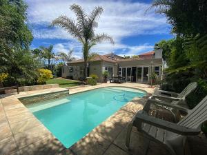 a house with a swimming pool in front of a house at Lovely Family Home in Durbanville in Durbanville