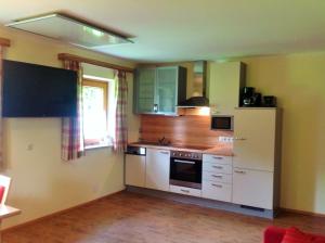 uma cozinha com armários brancos e um frigorífico branco em s'Hoamatl em Neukirchen am Grossvenediger