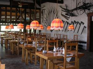 un restaurante con mesas de madera, sillas y luces en Logis Hôtel Relais Paris Bale - Restaurant La Mangeoire en Montieramey