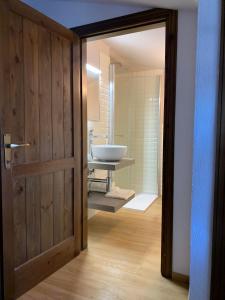 een badkamer met een witte wastafel en een deur bij La Casetta in Bosco Chiesanuova