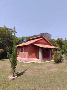 una pequeña casa roja con un árbol delante en Recanto da Serra, en São Thomé das Letras