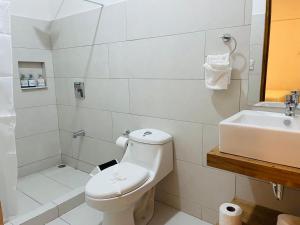 La salle de bains blanche est pourvue de toilettes et d'un lavabo. dans l'établissement Hotel Ocotal Bed & Breakfast, à Ocotal