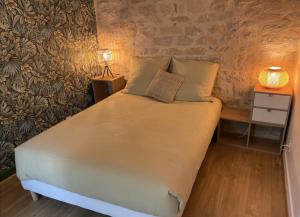 a bed with two pillows and a table with a lamp at Chambre Cocoon dans une maison avec SPA et jardin en centre ville in Dijon