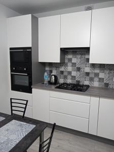 una cucina con armadi bianchi, tavolo e piano cottura di Apartament Łańcut a Łańcut