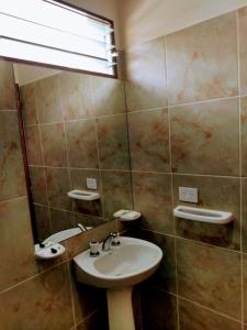 La salle de bains est pourvue d'un lavabo et d'un miroir. dans l'établissement Cabañas Y Departamentos Bettylu, à Villa Cura Brochero