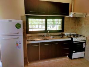 cocina con nevera blanca y fregadero en Cabañas Y Departamentos Bettylu en Villa Cura Brochero