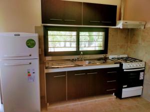 a kitchen with a white refrigerator and a sink at Cabañas Y Departamentos Bettylu in Villa Cura Brochero
