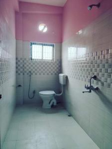 a bathroom with a toilet and a pink wall at Nilachal Homes in Guwahati