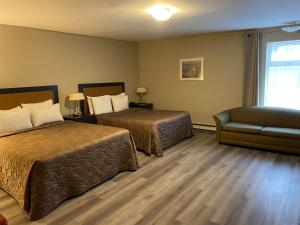 a hotel room with two beds and a chair at Hotel & Suites Monte-Cristo in Quebec City