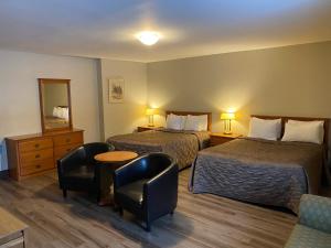 ein Hotelzimmer mit 2 Betten, einem Tisch und Stühlen in der Unterkunft Hotel & Suites Monte-Cristo in Québec