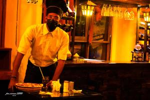 a man wearing a face mask standing behind a counter at Hotel Alpamayo Guest House in Huaraz