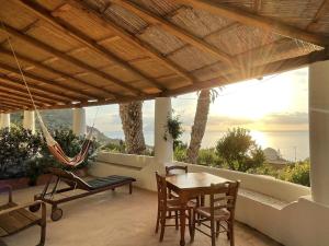 a porch with a hammock and a table and chairs at Hotel La Locanda Del Postino in Pollara