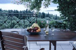 una mesa de madera con un bol de frutas y copas de vino en Evreti Villa with Stunning views, near Fiscardo, en Fiskardho