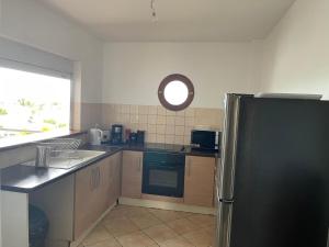 a kitchen with a black refrigerator and a window at TURQUOISE CARAIBES in Les Trois-Îlets