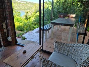 een patio met een tafel en stoelen en een tafel bij Riversbend Cottage in Bushmans River Village