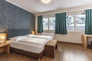 a hotel room with a bed and two windows at Appartements Landhaus Hubertus Wellness & Breakfast in Schladming