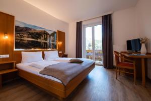 a bedroom with a bed and a desk with a computer at Hotel Restaurant Platzer in Gmünd in Kärnten