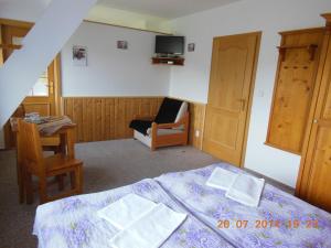 a bedroom with a bed and a chair and a tv at Pension Krakonoš in Špindlerův Mlýn