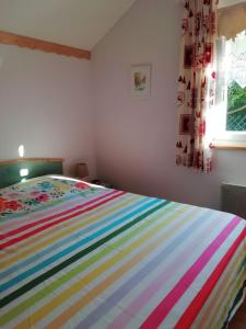 een kleurrijk gestreept bed in een slaapkamer met een raam bij Le Chalet Bel Air in Oderen