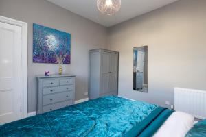 a bedroom with a bed and a painting on the wall at Stylish George Street Apartment in Peebles