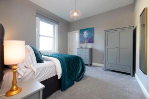 a bedroom with a bed and a dresser and a window at Stylish George Street Apartment in Peebles