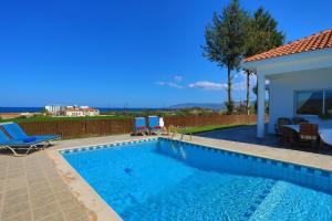 a swimming pool with two chairs and a house at The Vines in Lachi