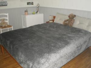 a large bed with a teddy bear sitting on it at les Mésanges bleues in Saint-Jouan-de-lʼIsle