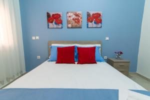 a blue bedroom with a large bed with red pillows at Nikopoleos 41 in Preveza