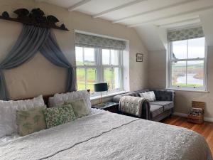 a bedroom with a bed and a couch and windows at Ty Capel in Llanidloes