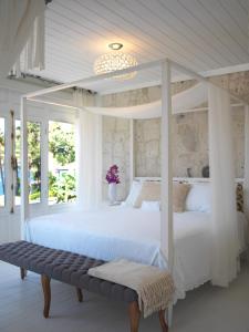 Dormitorio blanco con cama con dosel y banco en Sabrinas Haus - Adult Only +14, en Bozburun