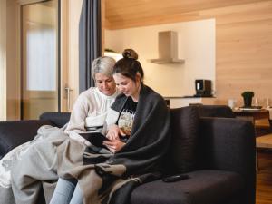 two women sitting on a couch looking at a tablet at Ferienwohnung z'übrmello in Mellau