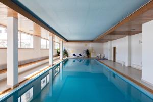a swimming pool with blue water in a building at Charming Studio facing Piz Rosatsch in St. Moritz