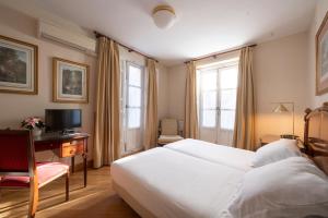 a bedroom with a bed and a desk with a television at Miranda & Suizo in San Lorenzo de El Escorial