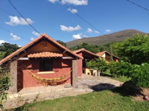 una casa de ladrillo rojo con montañas en el fondo en Recanto da Serra, en São Thomé das Letras