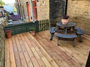 a table and chairs on a wooden deck at Heather Bank Cottage, Halifax. Yorkshire. HX2 7DD in Halifax