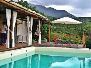 a house with a swimming pool and an umbrella at LOFT DE MONTAÑA -LaS RABONAS - PISCINA EXCLUSIVA in Las Rabonas