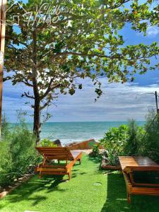 two benches sitting on the grass near the ocean at CHILL HOUSE by the beach in Phu Quoc