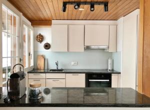 a kitchen with white cabinets and a black counter top at Chalet Pironnet with BEST Views, Charm and Comfort! in Lauterbrunnen