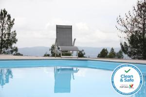 a chair sits next to a swimming pool with the clean and safe sign at Casa Quelha da Presa in Espinho