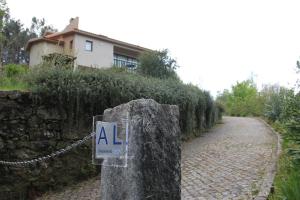 een bord op een stenen muur naast een weg bij Casa Quelha da Presa in Espinho