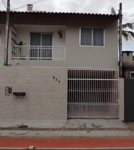 a white house with a gate and a balcony at Casa em Balneário Camboriú - próxima à praia in Balneário Camboriú