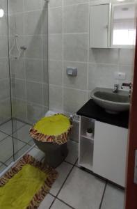 a bathroom with a sink and a toilet with a green lid at Casa em Balneário Camboriú - próxima à praia in Balneário Camboriú