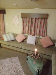 a living room with a couch with a candle on a table at Summer Breeze in Bude