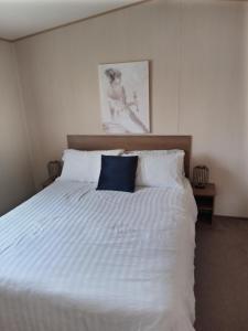a bedroom with a white bed with a blue pillow at Summer Breeze in Bude