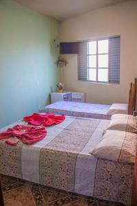 two beds in a room with red roses on them at Pousada da Mica in Carrancas