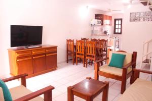 ein Wohnzimmer mit einem TV und einem Esszimmer in der Unterkunft Casa Duplex 3 Suítes em Condomínio in Porto Seguro
