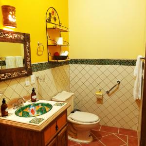 a yellow bathroom with a toilet and a sink at La Casona Chapala in Chapala