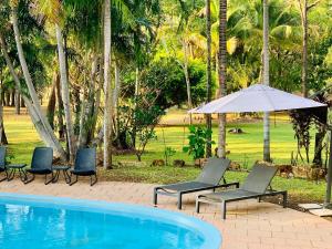 two chairs and an umbrella next to a swimming pool at Breeze Holiday Parks - Mary River in Marrakai